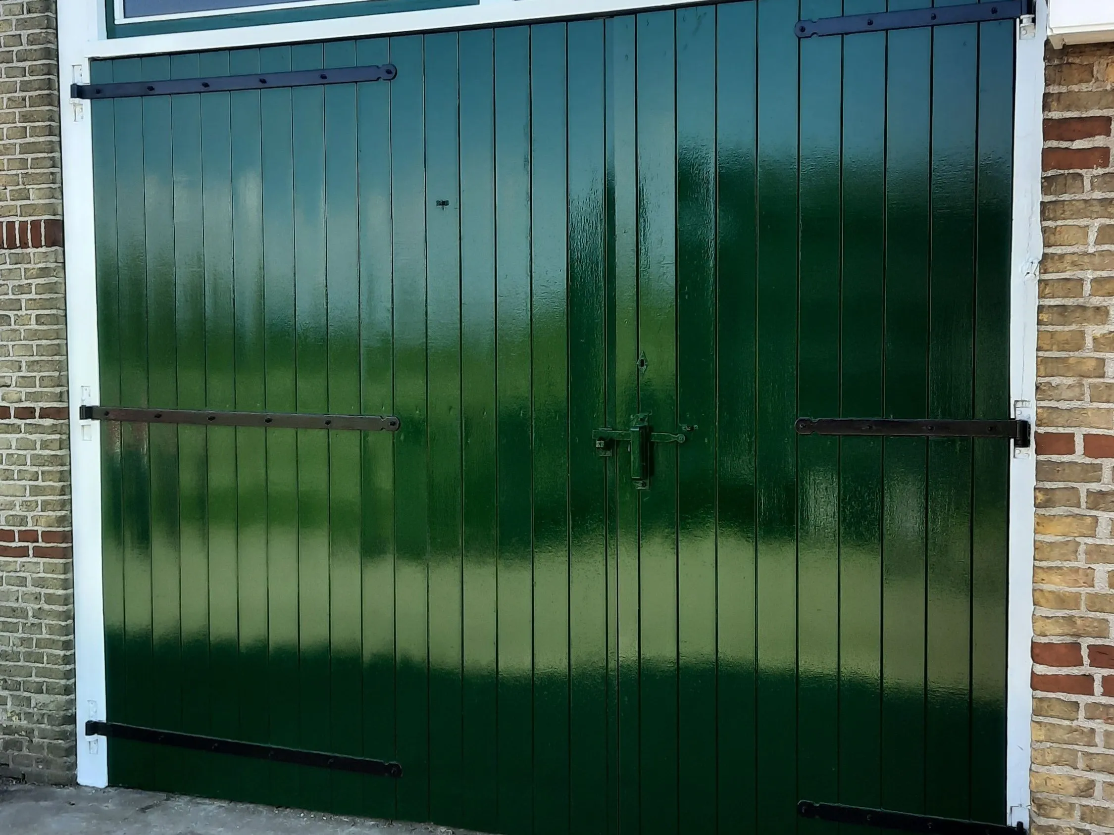 Dezelfde garagepoort, glanzend nieuw groen geschilderd door Schilderwerken Chris Postma