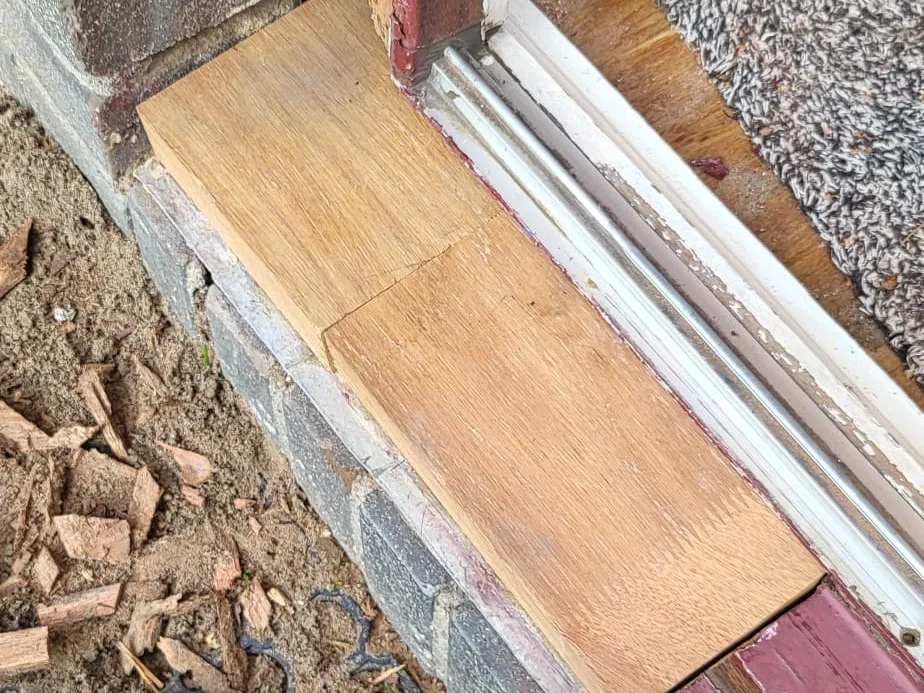 Dezelfde onderdorpel met een nieuw stuk hout ingezet, klaar om af te werken