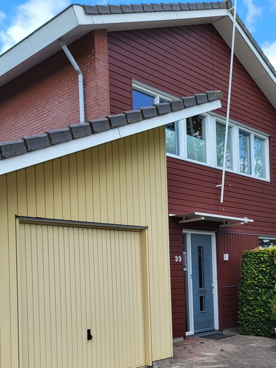 Woonhuis met een geel geschilderde houten gevel en een garagedeur